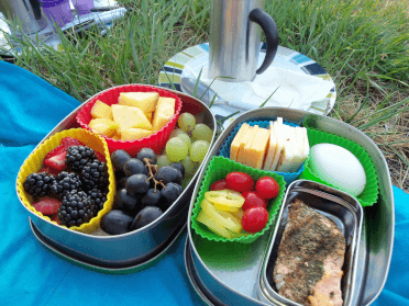 Two lunchboxes utilising dividers to separate a range of different picnic foods to consume on a walking holiday.